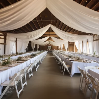 Wedding Decor Rental - Ceiling draping above beautiful tables with white linens, gold chargers, linen napkins, pillar candles, glass votives candles.